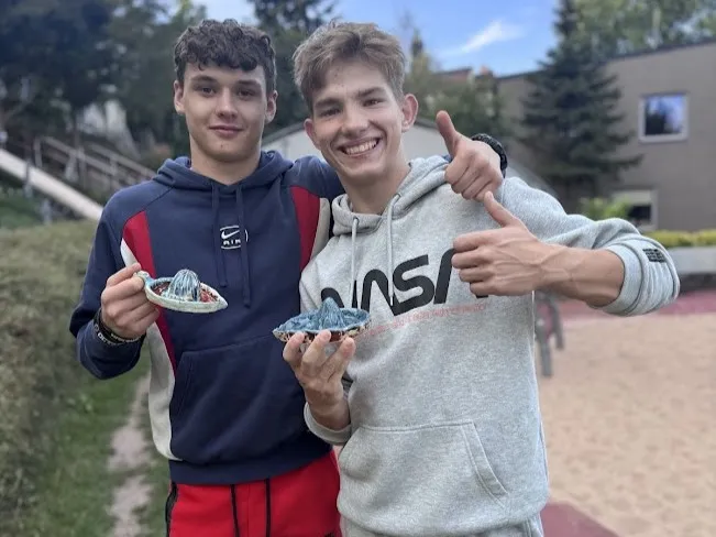 Warsztaty ceramiczne - dwóch uczniów zadowolonych po warsztatach przedstawia swoje prace